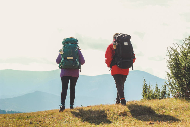 Girl and man hikers in mountains. Travel backpacks and clothing. - Foto, imagen