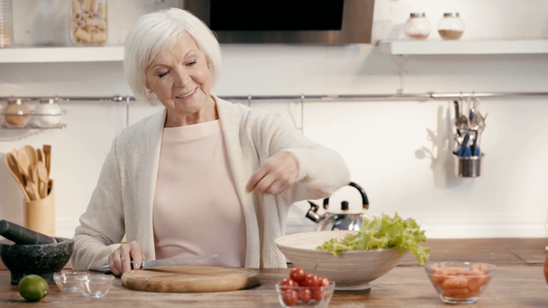 smiling woman adding bell pepper to salad  - Záběry, video