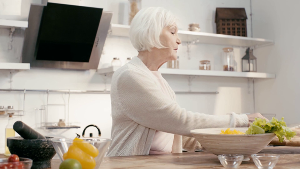 uśmiechnięta kobieta dodając cięty papryka do miski   - Materiał filmowy, wideo