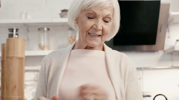 Lächelnde Frau würzt Salat mit Salzmühle - Filmmaterial, Video