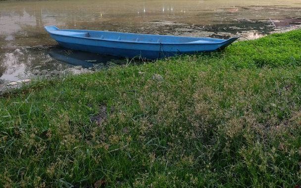 A small blue boat by the river. A river with muddy waters. - Photo, Image