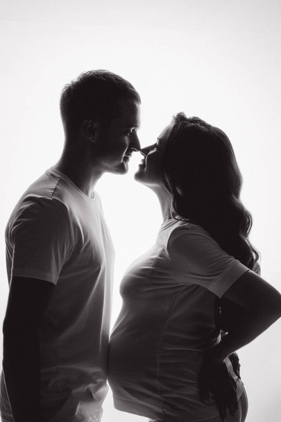 Front view of silhouettes of young couple waiting and caring about baby. Pregnant woman touching nose of her husband. Concept of parenthood and pregnant. - Photo, Image