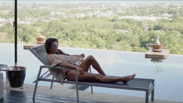 Nő fekszik nyugágyon a hotel medence teraszán - Felvétel, videó