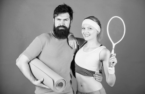 Вместе мы играем. Вместе мы победим. Сильные мышцы и тело. Счастливая женщина и бородатый мужчина тренируются в спортзале. Спортивное оборудование. Спортивная пара тренировки с фитнес-коврик и теннисная ракетка. Атлетический успех
 - Фото, изображение