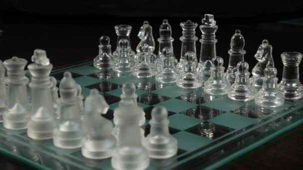 Close-up de mãos masculinas e femininas jogando xadrez de vidro em um fundo escuro
 - Filmagem, Vídeo