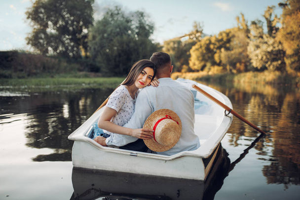 Miłość para w łodzi na cichym jeziorze w letni dzień. Romantyczna randka, wycieczka łodzią, mężczyzna i kobieta spacerujący wzdłuż rzeki - Zdjęcie, obraz