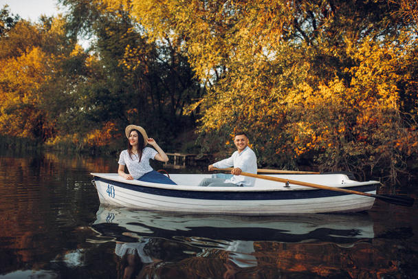 Love couple in boat on quiet lake at summer day, daydream, side view. Romantic date, boating trip, man and woman walking along the river - Photo, Image