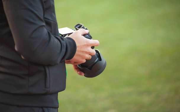 A man holds a camera in his hands on a blurry green background, a professional photographer makes pictures - Photo, Image