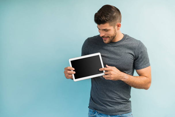 Молодой мужчина трогает цифровой планшет с чистым экраном в студии
 - Фото, изображение