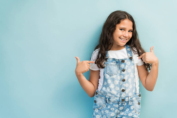 Happy preadolescent female child pointing at herself while against plain background - Fotoğraf, Görsel