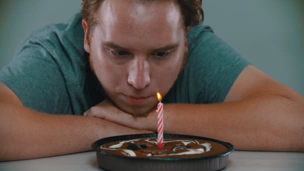Mężczyzna zdmuchuje świeczkę na torcie urodzinowym. - Materiał filmowy, wideo