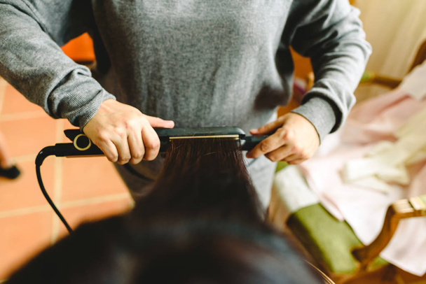 Cabeleireiro alisando o cabelo de uma mulher com um alisador de cabelo
. - Foto, Imagem