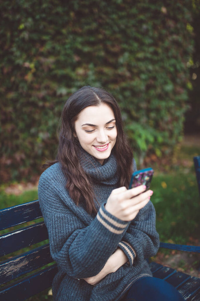 屋外でスマートフォンを持つ若い女性 - 写真・画像