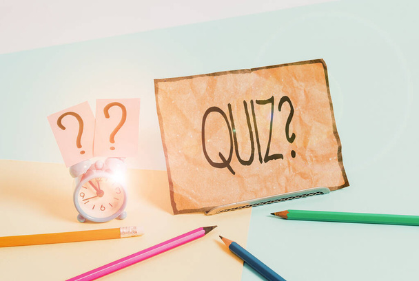 Writing note showing Quiz Question. Business photo showcasing test of knowledge as competition between individuals or teams Mini size alarm clock beside stationary on pastel backdrop. - Photo, Image