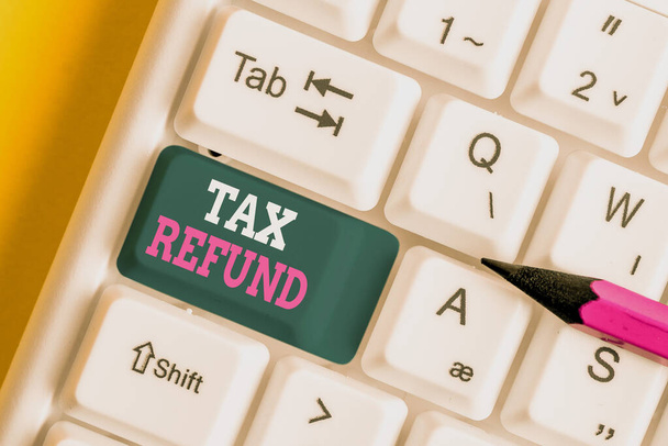 Writing note showing Tax Refund. Business photo showcasing refund on tax when the tax liability is less than the tax paid White pc keyboard with note paper above the white background. - Photo, Image