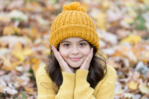 Warm woolen accessory. Girl long hair happy face autumn nature background. Lovely season. Keep warmest this autumn. Child in yellow hat outdoors. Autumn skin care routine. Kid wear warm knitted hat - Photo, Image