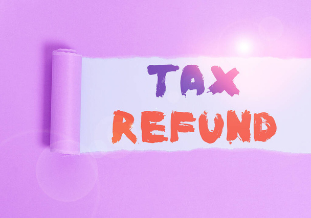 Handwriting text Tax Refund. Concept meaning refund on tax when the tax liability is less than the tax paid Cardboard which is torn in the middle placed above a plain table backdrop. - Photo, Image