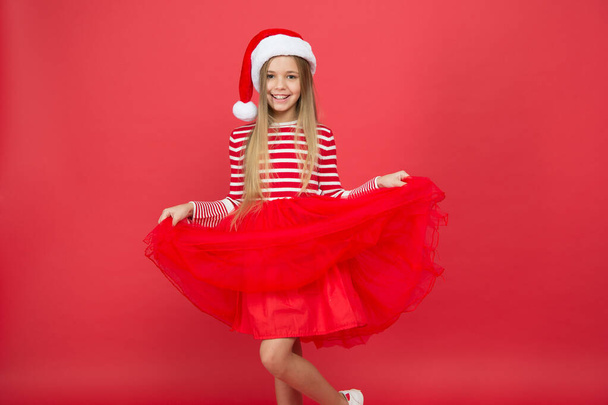 Fancy skirt. Child santa costume believe in miracle. Girl little kid on red background. Merry christmas and happy new year. Christmas party. Cheerful girl having fun christmas eve. Best wishes - Photo, Image