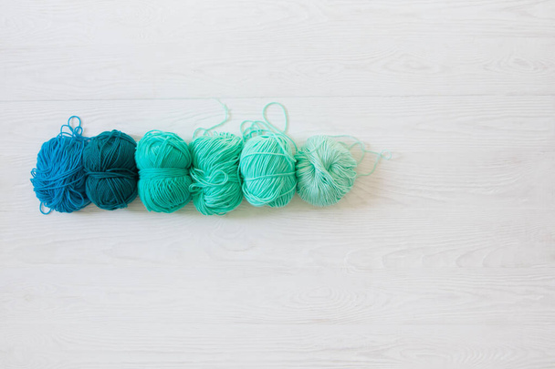 Yarn of green, turquoise, aquamarine and blue colors. White wood - Foto, imagen
