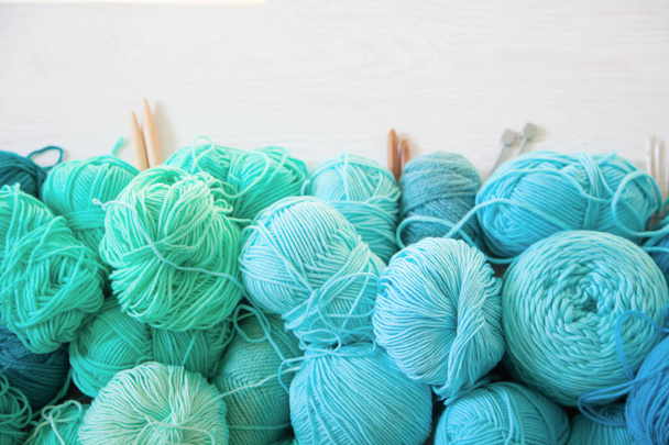 Yarn of green, turquoise, aquamarine and blue colors. White wood - Φωτογραφία, εικόνα