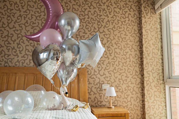Home bedroom interior. Holiday ballons and stuffed flamingo toy on the bed. Birthday gift for girl and decoration - Foto, Bild
