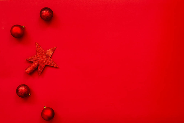 Boże Narodzenie tło - płaski układ czerwonej gwiazdy Bożego Narodzenia i piłki na czerwonym tle. Przestrzeń kopiowania. - Zdjęcie, obraz
