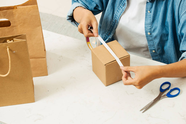 Woman packing cardboard boxes using tape dispenser - Foto, Imagen