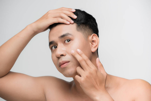 Skin problems. Worried man with a stubble examining his face  - Photo, Image