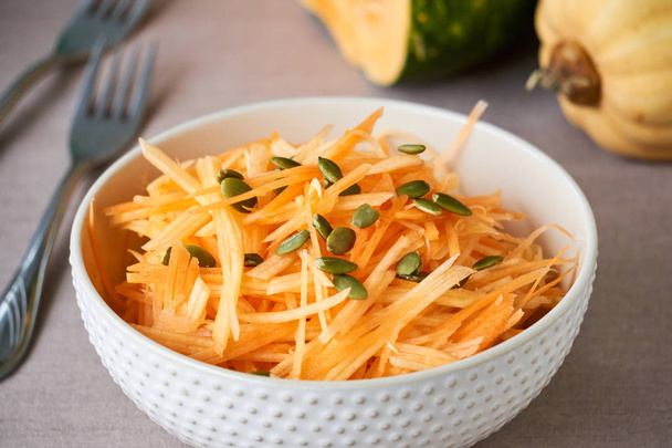 Salad with raw pumpkin and carrots in a white bowl                                - Zdjęcie, obraz
