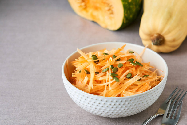 Salad with raw pumpkin and carrots in a white bowl                                - Foto, imagen