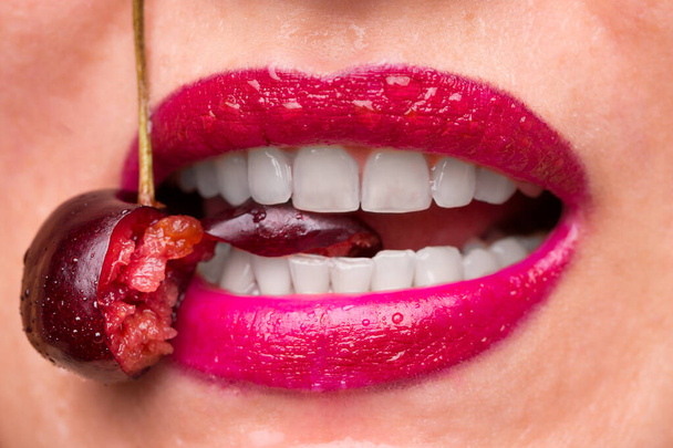 The girl bites a ripe cherry. - Fotoğraf, Görsel