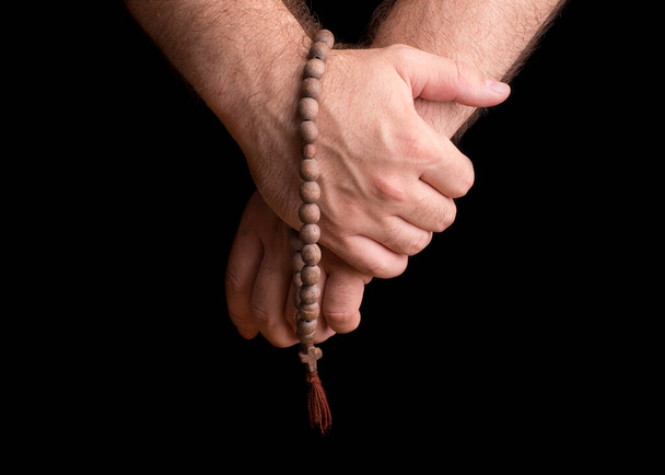 Hands of a male priest with a wooden rosary. - Foto, imagen