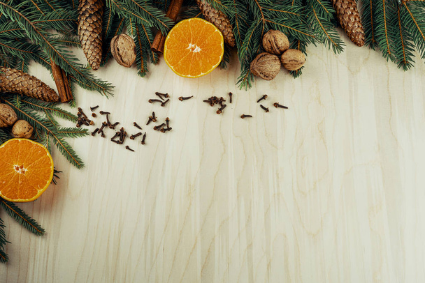 Marco navideño hecho con ramitas, conos, nueces, canela, clavos y cítricos aislados sobre fondo de madera
 - Foto, Imagen