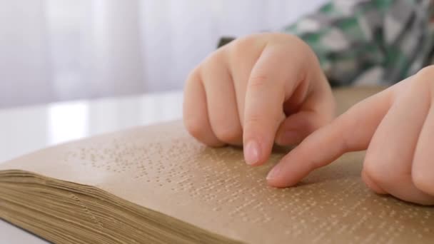 slepý kluk ruce čtení braille knihy se symboly písmem pro zrakově postižené zblízka sedí u stolu - Záběry, video