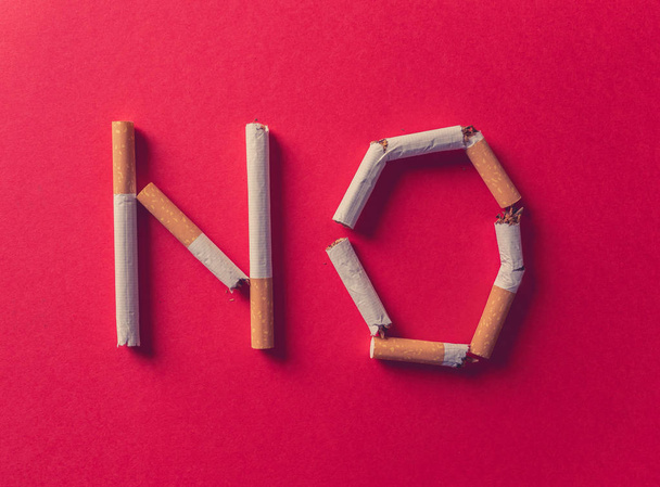 NO written with broken cigarettes isolated on red background. Conceptual image with advertising style for World no tobacco day and stop smoking campaign concept. - Fotó, kép