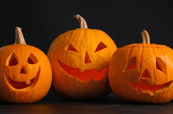 Pumpkins with scary faces on black background. Halloween traditi - Zdjęcie, obraz