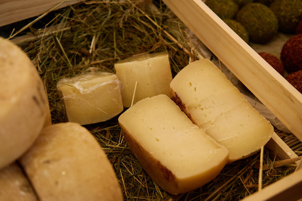 Голова сиру крупним планом лежить в коробці на сіні
 - Фото, зображення