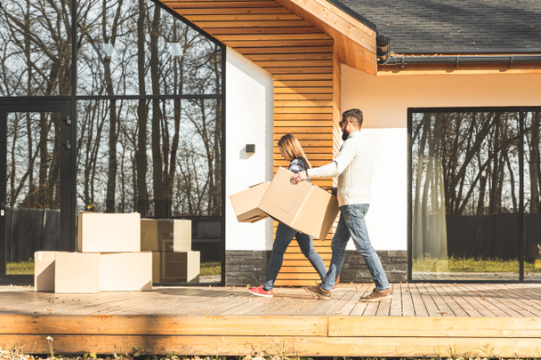 Genç çift yeni bir eve taşınıyor. Aile bir ev aldıktan sonra kutular dolusu eşya taşır.. - Fotoğraf, Görsel