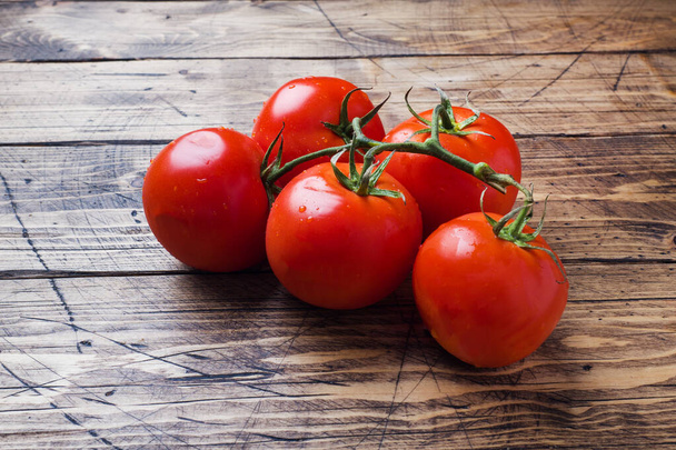 Red ripe tomatoes on a branch. Wooden background copy space. - Фото, зображення
