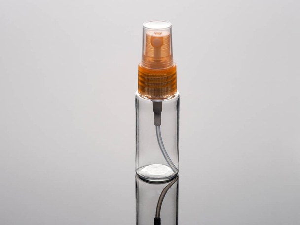 Kosmetik-Sprühflasche vertikal auf grauem Hintergrund mit Reflex - Foto, Bild