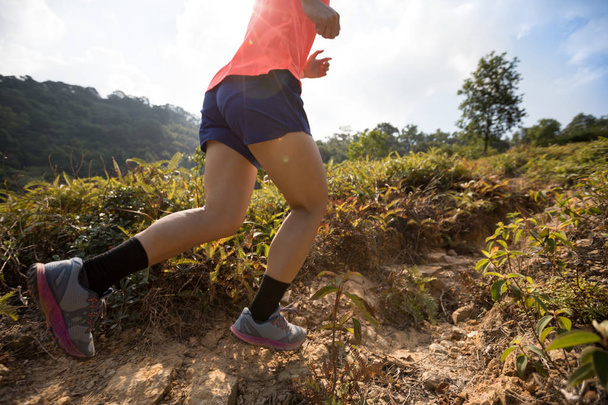 Woman ultramarathon runner running up on mountain slope in tropical forest  - Photo, Image