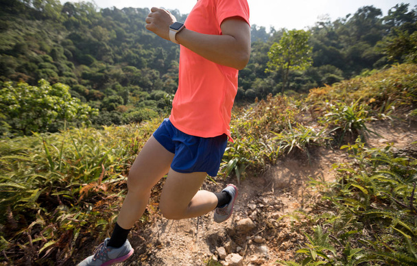 Nő ultramaraton futó futó futó lefelé a hegy lejtőjén a trópusi erdőben - Fotó, kép