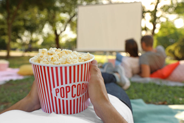 Patlamış mısırlı genç adam açık hava sinemasında film izliyor, yakın çekim. Metin için alan - Fotoğraf, Görsel