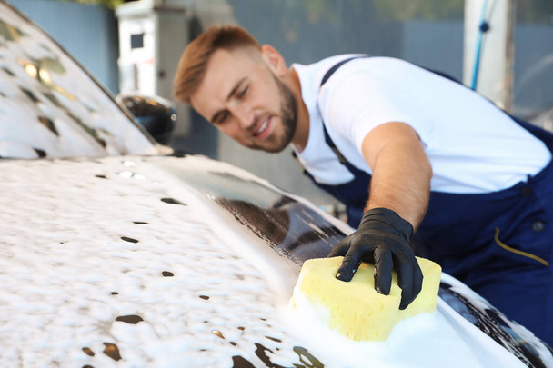 Young worker cleaning automobile with sponge at car wash - Zdjęcie, obraz