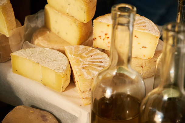 Большие кусочки сыра. В раме бутылки с оливковым маслом
 - Фото, изображение