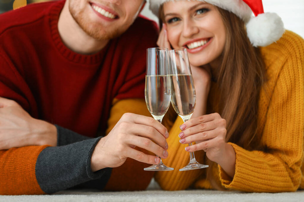Happy young couple with glasses of champagne at home, focus on hands. Christmas celebration - Φωτογραφία, εικόνα