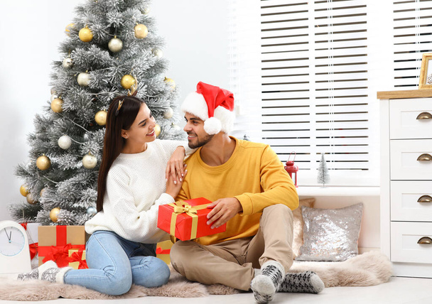 Feliz pareja joven con regalo de Navidad en casa - Foto, imagen
