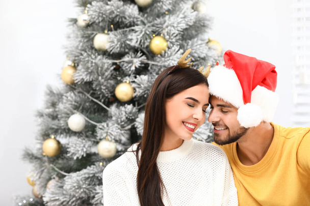 Happy young couple near Christmas tree at home - Fotoğraf, Görsel