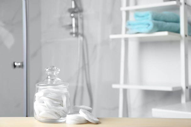 Хлопчатобумажные прокладки на деревянном столе в ванной комнате
 - Фото, изображение
