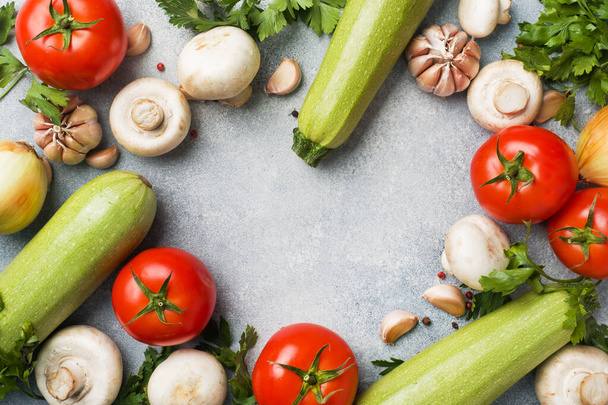 Set of different seasonal vegetables on a gray concrete background. Tomato zucchini onion garlic mushrooms parsley spices. Frame copy space. - Zdjęcie, obraz